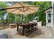 An outdoor dining table with umbrella and built in grill area overlooks a lush wooded backyard at 3933 Ayrshire Pl, Charlotte, NC 28210