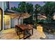 Well lit outdoor dining table with umbrella overlooking a lush wooded backyard at dusk at 3933 Ayrshire Pl, Charlotte, NC 28210