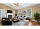 Bright living room features a fireplace, ceiling fan, and large windows providing natural light at 6915 Norchester Ct, Charlotte, NC 28227