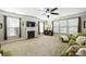 A large living room with a fireplace, ceiling fan, many windows, and comfortable green seating at 79115 Ridgehaven Rd, Lancaster, SC 29720