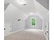 An attic bedroom features neutral carpet, white walls, two storage nooks, and a window with greenery outside at 8032 Turnberry Ln, Stanley, NC 28164