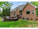 Brick home featuring an outdoor patio space, lush green lawn, and well-maintained landscaping at 8032 Turnberry Ln, Stanley, NC 28164