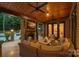 A covered outdoor living space featuring a fireplace, wood ceiling, and comfortable seating at 1102 Anniston Pl, Wesley Chapel, NC 28079