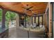 A covered outdoor living space featuring a fireplace, wood ceiling, and comfortable seating at 1102 Anniston Pl, Wesley Chapel, NC 28079