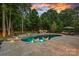 A luxurious swimming pool and jacuzzi featuring a slide, in-pool seating, and mature trees at 1102 Anniston Pl, Wesley Chapel, NC 28079