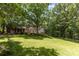 View of a large backyard with green lawn, a two-story brick home, and tall trees at 1468 Woodhurst Dr, Rock Hill, SC 29732