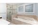 Well-lit bathroom showcases a tiled shower and separate tub beneath windows at 1468 Woodhurst Dr, Rock Hill, SC 29732