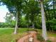 Lush backyard featuring a brick path, mature trees, and gazebo at 15546 Thompson Rd, Mint Hill, NC 28227