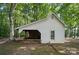 White outbuilding with an attached covered area for storage and projects at 15546 Thompson Rd, Mint Hill, NC 28227