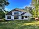 Modern farmhouse exterior showcasing a spacious yard and covered patio with black trim windows under a clear blue sky at 6712 Cove Ln, Sherrills Ford, NC 28673