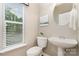 Cozy powder room with a pedestal sink, a toilet, and a bright window at 9802 Sky Vista Dr, Huntersville, NC 28078