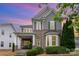 Beautiful two-story home featuring mixed siding, brick accents, lush landscaping and dusk lighting at 9802 Sky Vista Dr, Huntersville, NC 28078