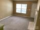 Bright living room featuring neutral walls, carpet flooring, a fireplace, and a large window that brings in natural light at 1012 Kings Mountain Ln, Gastonia, NC 28054