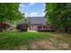 Large grassy backyard bordered by mature trees and a wooden deck at 1033 Marguerite Dr, Lowell, NC 28098