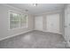 This bedroom features neutral-colored walls, two closets, plush carpet, and a large window at 1033 Marguerite Dr, Lowell, NC 28098
