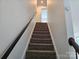 Carpeted staircase with a wooden handrail leading to the upper level of the home at 106 Calderdale Ln, Charlotte, NC 28262