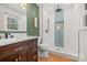 Modern bathroom with a walk-in shower, wood cabinets, and decorative green accent wall at 124 Hunters Creek Dr, Mooresville, NC 28115