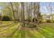 Spacious backyard featuring mature trees, a storage shed, and a wooded perimeter at 12628 Waterfall Pl, Charlotte, NC 28278