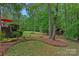 Lush backyard landscape with an outdoor pavilion and stone fireplace providing tranquil outdoor living at 1305 Anniston Pl, Wesley Chapel, NC 28079