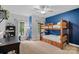 Charming bedroom featuring a wooden bunk bed, blue accent wall, and natural light from large windows at 1305 Anniston Pl, Wesley Chapel, NC 28079