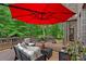 Relaxing deck area featuring stylish wicker furniture, a vibrant red umbrella, and lush landscaping at 1305 Anniston Pl, Wesley Chapel, NC 28079
