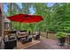 Beautifully appointed deck with comfortable seating, red umbrella, and serene wooded views at 1305 Anniston Pl, Wesley Chapel, NC 28079