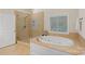 Bright main bathroom featuring a soaking tub, separate glass shower, and a large window for natural light at 1305 Anniston Pl, Wesley Chapel, NC 28079