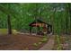 Secluded outdoor fireplace and kitchen area with seating, lush greenery, and stone path at 1305 Anniston Pl, Wesley Chapel, NC 28079