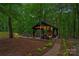 Charming outdoor fireplace pavilion set in a lush, wooded landscape, ideal for entertaining and relaxation at 1305 Anniston Pl, Wesley Chapel, NC 28079