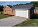This exterior shot showcases a brick home, attached garage and gravel driveway in front at 1488 Ernest Rd, York, SC 29745