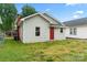 A charming exterior view with light gray siding, red door, a brick chimney, and well-kept lawn at 18 Douglas Nw Ave, Concord, NC 28025
