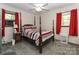 Cozy bedroom featuring a four-poster bed, bright red curtains, and natural light from the two windows at 212 Davies Cir, Cleveland, NC 27013