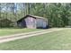 The detached outbuilding features a garage door and ample storage space on a grassy lot at 212 Davies Cir, Cleveland, NC 27013
