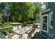 Outdoor wooden deck with glass table and hot tub surrounded by lush green trees and beautiful landscaping at 2278 Jon Chris Dr, Harrisburg, NC 28075