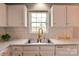 Close-up of the kitchen sink with white cabinets, subway tile backsplash, and a window above the sink at 301 Walkers Ridge Dr, Shelby, NC 28152