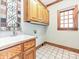 Well-lit laundry room with wood cabinets, classic white tile floors, and a sink at 3231 Karen Ln, Monroe, NC 28110