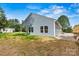View of home's rear with blue siding, green grass, rock landscaping, and blue skies at 3567 Farmfield Dr, Claremont, NC 28610