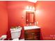 The bathroom features red walls, a mirror, a toilet, and a dark wood vanity with white countertops at 3837 1St Street Nw Ln, Hickory, NC 28601