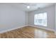 This bright, neutral bedroom includes gorgeous hardwood floors, a ceiling fan, and a window at 400 N Church St # 413, Charlotte, NC 28202
