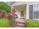 Charming front porch with brick steps, adorned with a beautiful rose bush and lush green hedges at 4227 Coopersdale Rd, Charlotte, NC 28273