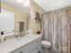 Bright bathroom featuring a shower/tub combination with patterned curtain, toilet, and single sink vanity with decorative lighting at 4346 Walker Rd, Charlotte, NC 28211