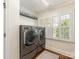 Well lit laundry room with shelving, stainless steel washer and dryer and plantation shutters at 4346 Walker Rd, Charlotte, NC 28211