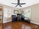 Home office featuring hardwood floors, two windows with plantation shutters, an overhead fan, and a dark-colored desk at 4346 Walker Rd, Charlotte, NC 28211