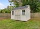 Backyard shed featuring a dark roof, double doors, and painted siding, surrounded by a lush lawn and privacy fence at 4346 Walker Rd, Charlotte, NC 28211