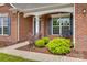 Up-close view of home's front entrance, featuring a covered porch and lush landscaping at 4926 Trayton Ave, Gastonia, NC 28056