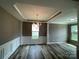 Open-plan living room featuring tray ceilings, decorative columns, wainscoting, and hardwood floors at 5619 Fenway Dr, Charlotte, NC 28273