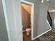 Small powder room, featuring modern fixtures, next to a staircase with floral wall art at 5619 Fenway Dr, Charlotte, NC 28273
