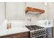 Close up of a kitchen range with custom vent hood and white marble backsplash at 5712 Runnel Way, Charlotte, NC 28215