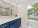 Renovated bathroom showcases a dark vanity, a large mirror, and a window with a view at 5817 Portburn Rd, Charlotte, NC 28211