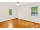 Empty bedroom with hardwood flooring and two bright windows illuminating the space at 5817 Portburn Rd, Charlotte, NC 28211